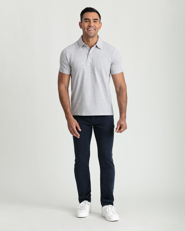 Man wearing light gray polo shirt and navy slim fit pants with white sneakers.