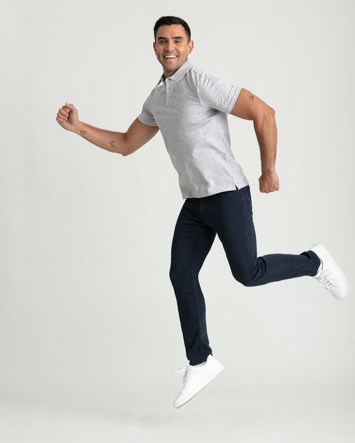 Man wearing light gray short-sleeve polo shirt and navy slim-fit pants with white sneakers.