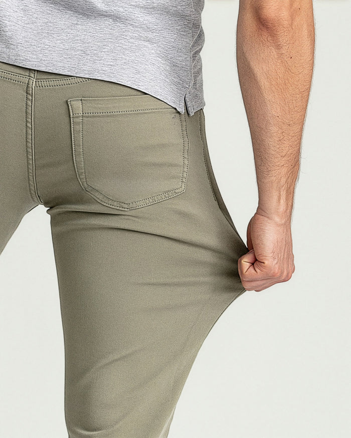 Man wearing light gray t-shirt and sage green slim fit pants with back pocket detail.