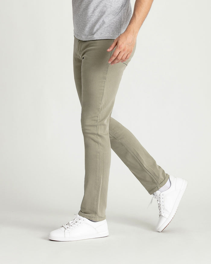 Man wearing light green slim fit pants with gray t-shirt and white sneakers.