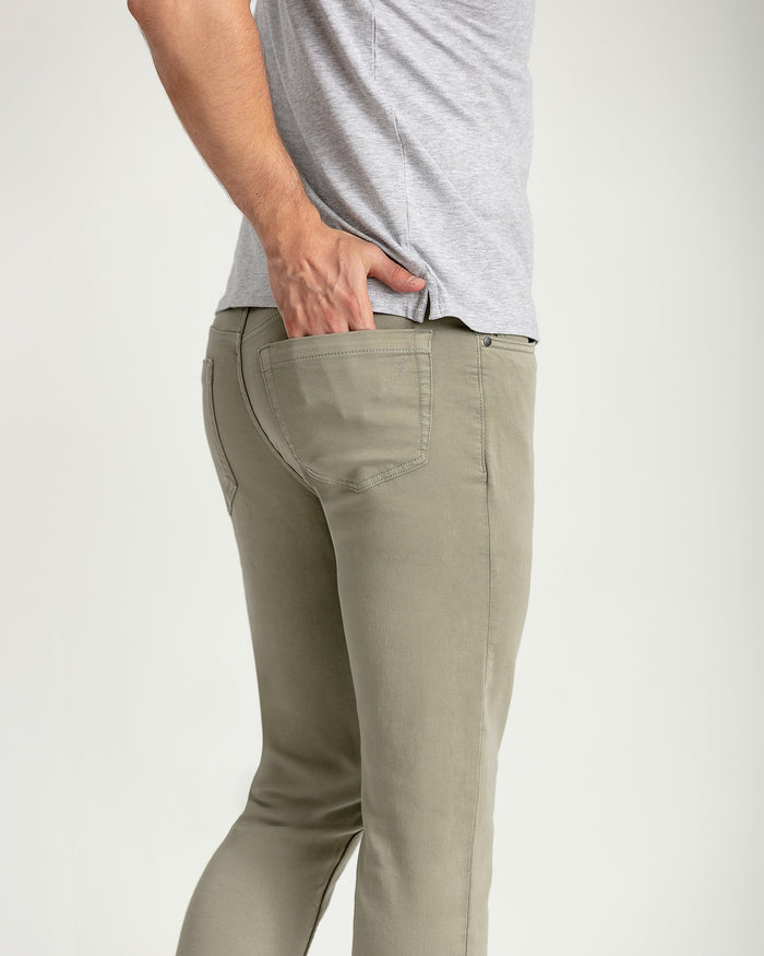 Light sage green slim fit pants with five-pocket styling worn with gray t-shirt.