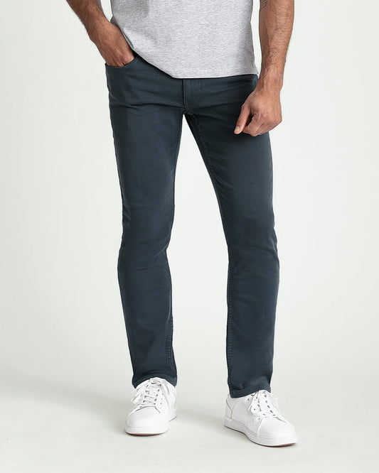 Man wearing gray t-shirt and dark slate slim fit jeans with white sneakers.