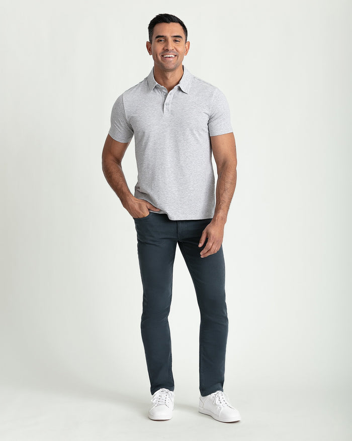 Man wearing light gray short-sleeve polo shirt and dark slate slim fit pants with white sneakers.