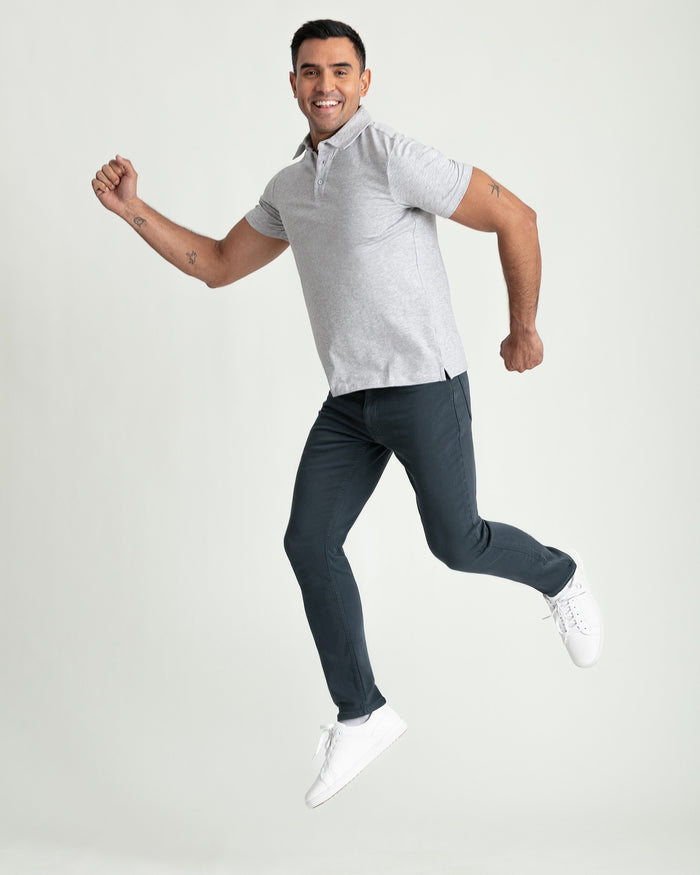 Man wearing light gray short-sleeve polo shirt and dark slate slim-fit pants with white sneakers.