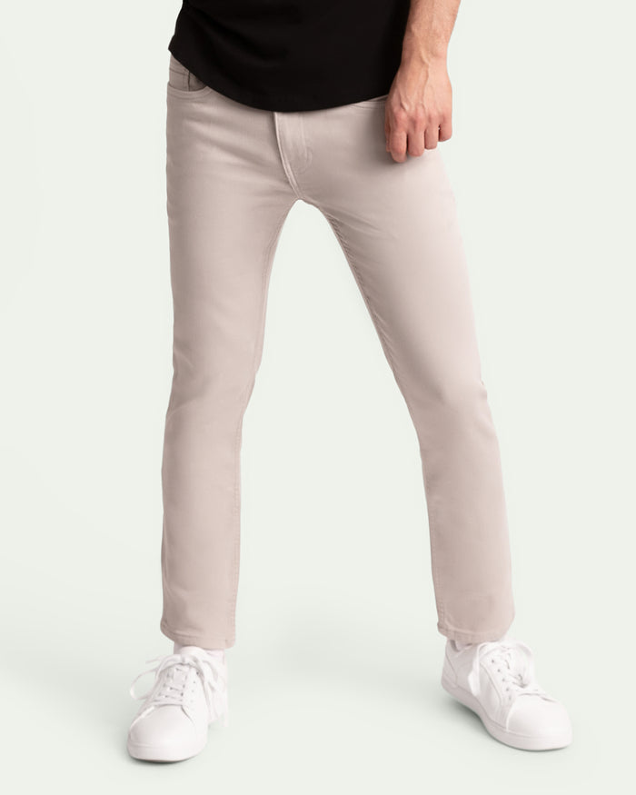 Man wearing light grey slim fit jeans with black shirt and white sneakers.