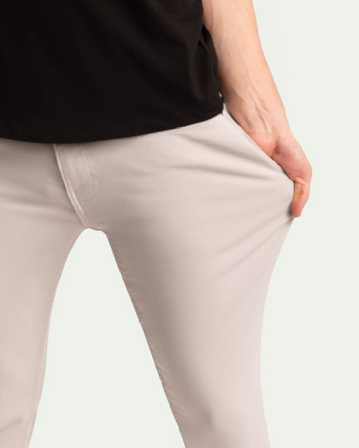 Light grey slim fit pants worn with black top, showing fitted waist and thigh detail.