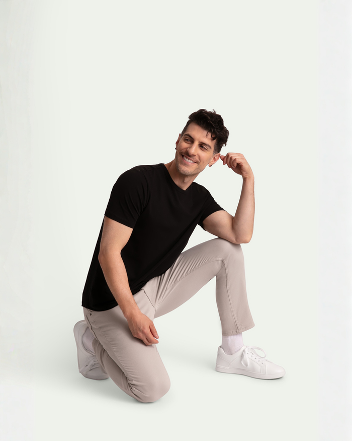 Man wearing black short-sleeve v-neck t-shirt and light grey slim fit pants with white sneakers.