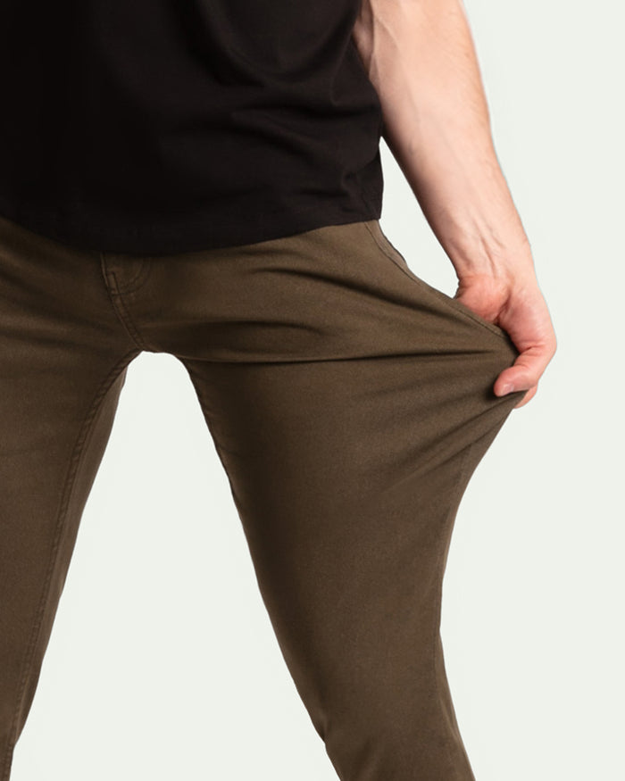Olive-colored slim fit pants on model wearing black shirt.