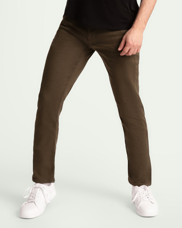 Man wearing olive-colored slim fit pants with white sneakers and black shirt.