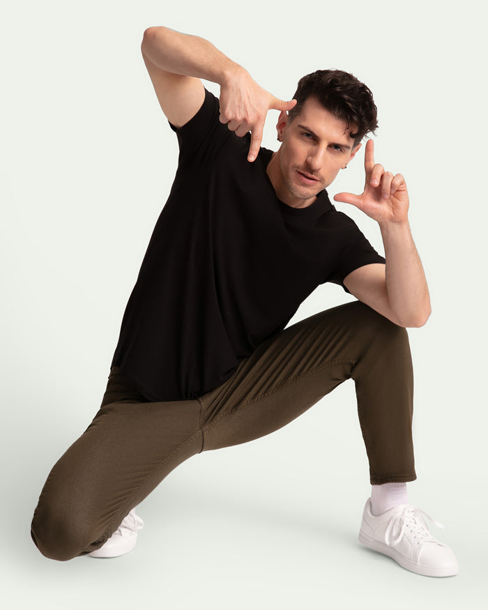 Man wearing black t-shirt and olive slim fit pants with white sneakers.