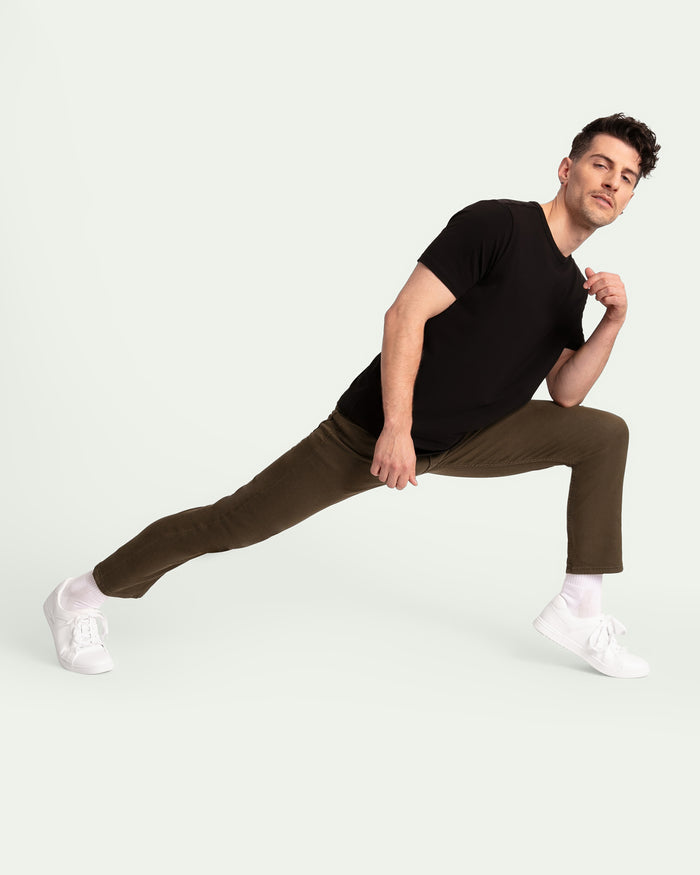 Man wearing black short-sleeve shirt and olive slim fit pants with white sneakers.