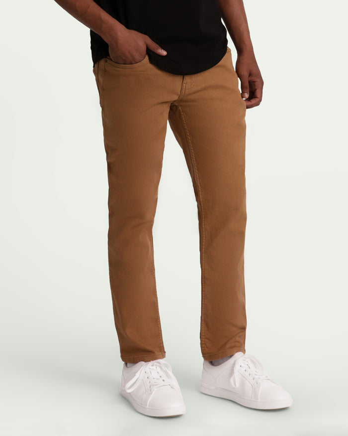 Brown slim fit chinos on a model wearing a black shirt and white sneakers.