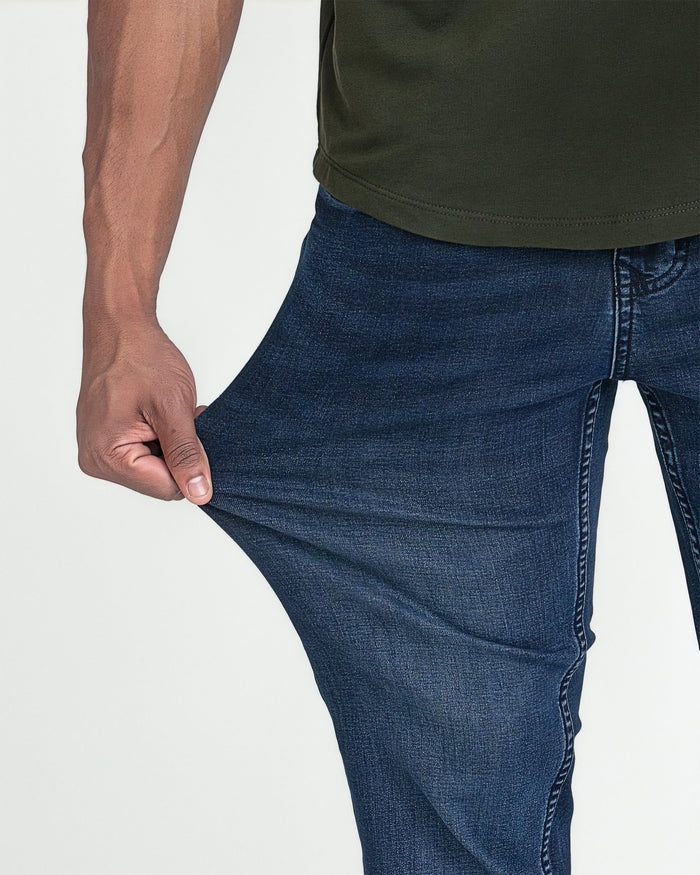 Man wearing dark blue slim fit jeans with olive-green t-shirt, showing fabric detail and fit.