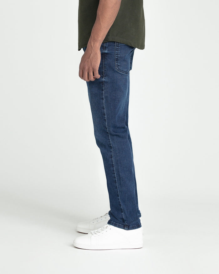 Dark blue slim fit jeans with a center seam, styled with a olive green shirt and white sneakers.