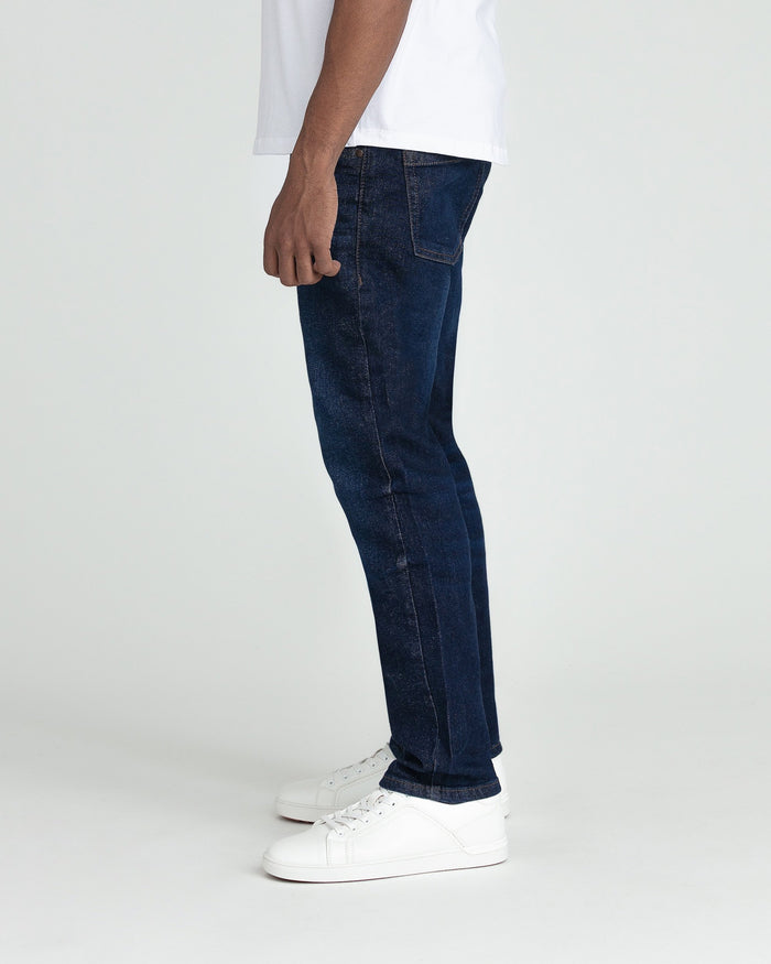 Man wearing dark blue slim fit jeans with white t-shirt and white sneakers, side view.