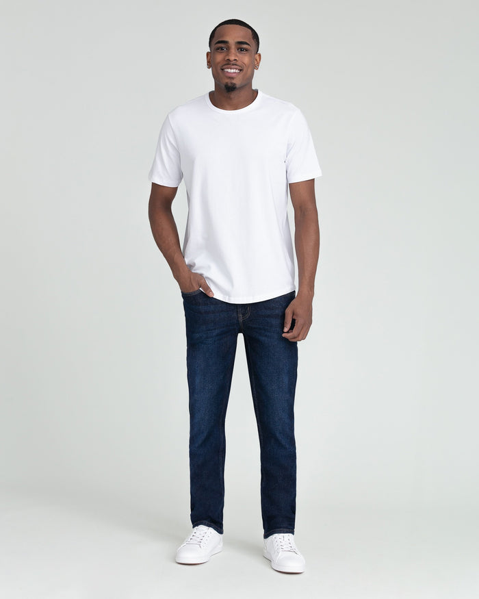 Man wearing white crew neck t-shirt and dark blue slim fit jeans with white sneakers.