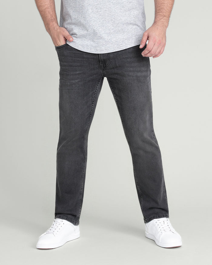 Man wearing light grey t-shirt with charcoal slim fit jeans and white sneakers.