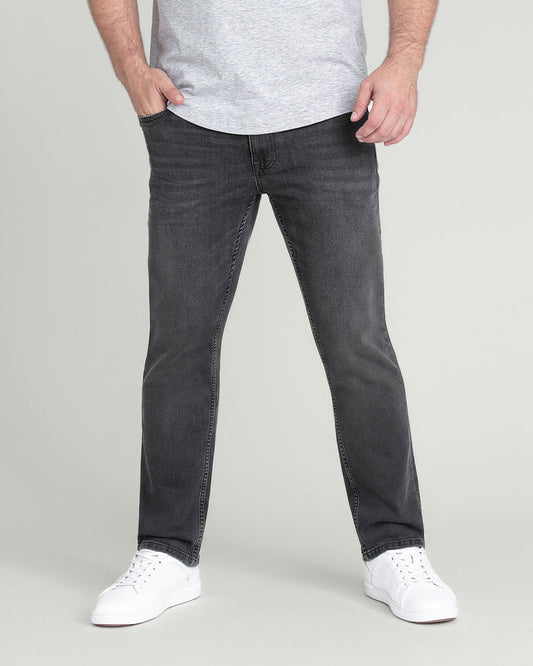 Man wearing light grey t-shirt with charcoal slim fit jeans and white sneakers.