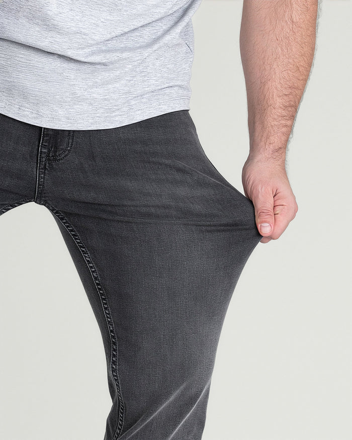 Man wearing light grey t-shirt and charcoal slim fit jeans, shown from waist down.