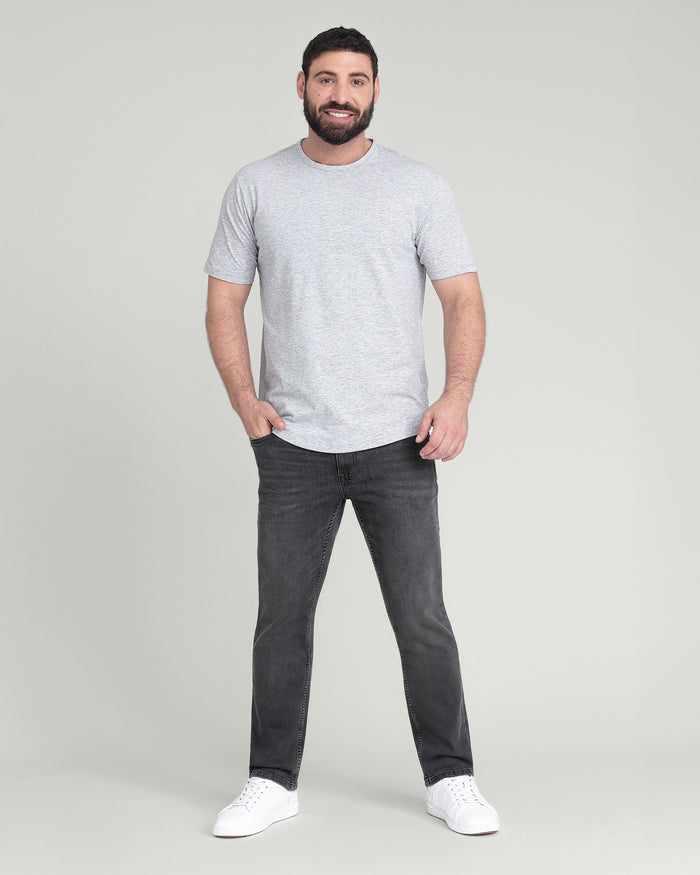 Man wearing light grey short-sleeve t-shirt and charcoal slim-fit jeans with white sneakers.