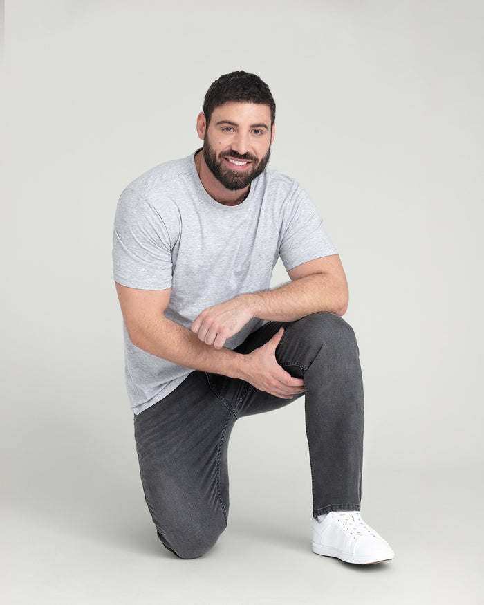 Man wearing light grey crew neck t-shirt with dark grey slim fit jeans and white sneakers.
