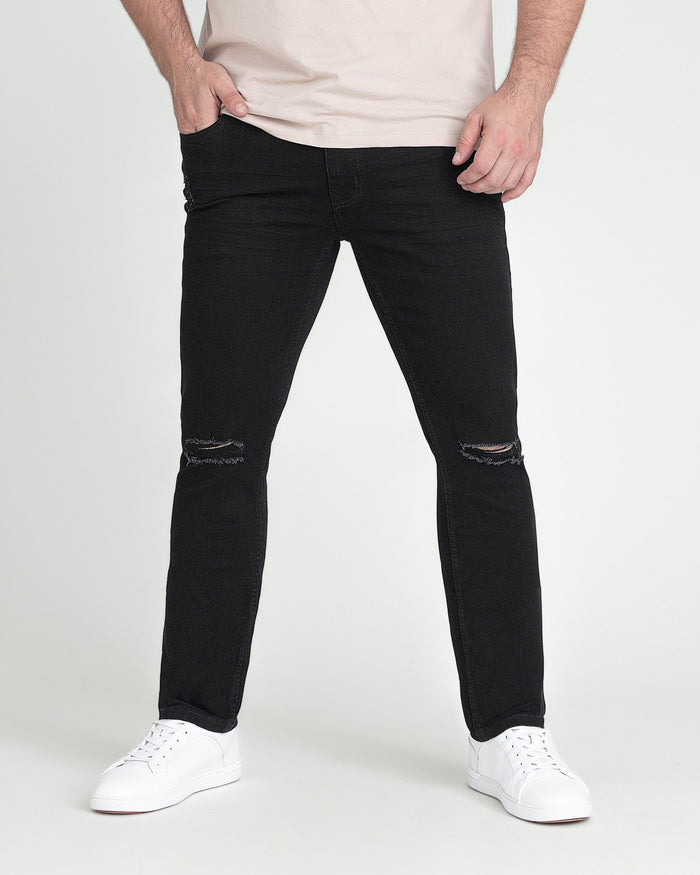 Black slim fit jeans with ripped knee details, worn with white sneakers and cream t-shirt.