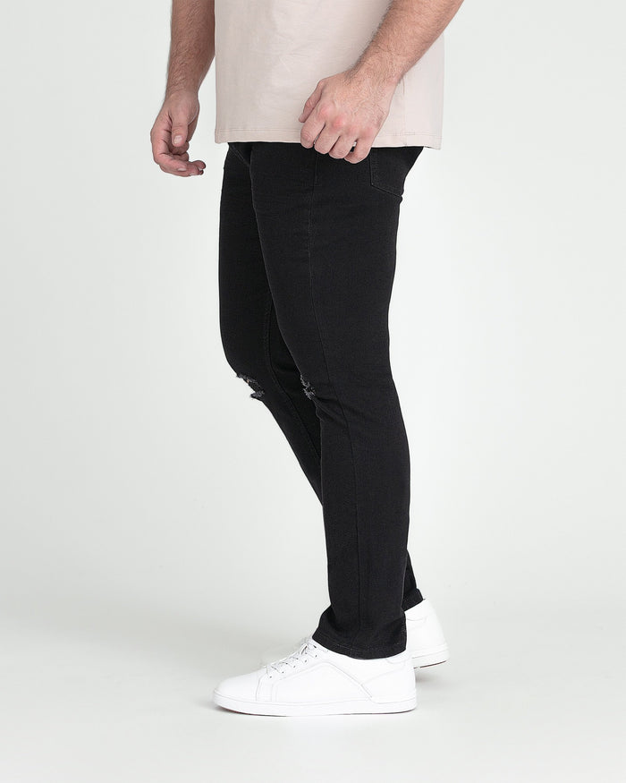 Black slim fit jeans with ripped thigh detail, worn with white sneakers.