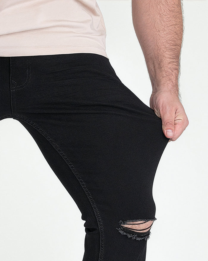 Black slim fit jeans with ripped knee detail, shown on model wearing white shirt.