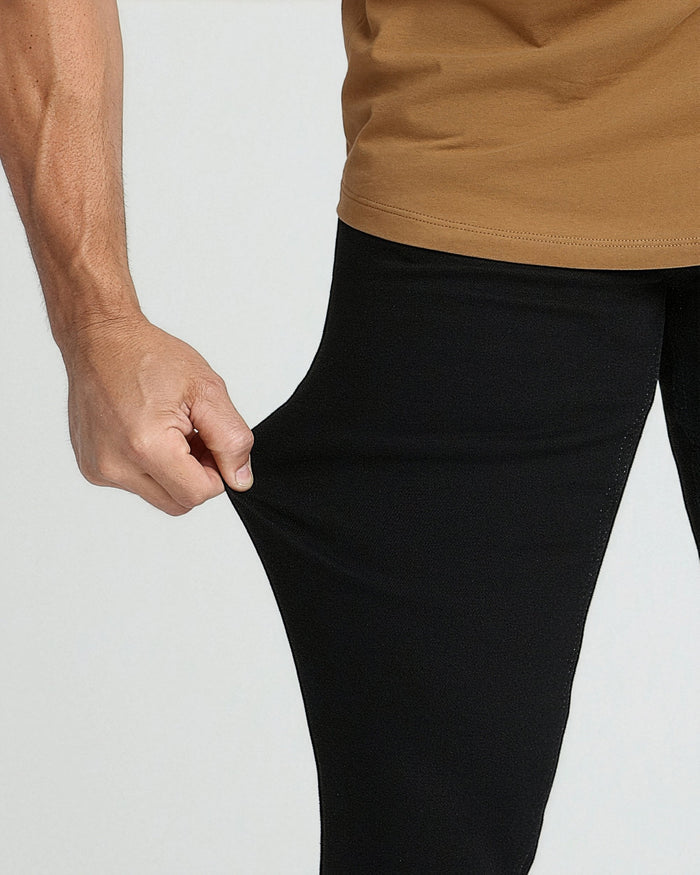 Man wearing tan short-sleeve shirt with black slim fit pants, showing fit at waist and thigh.