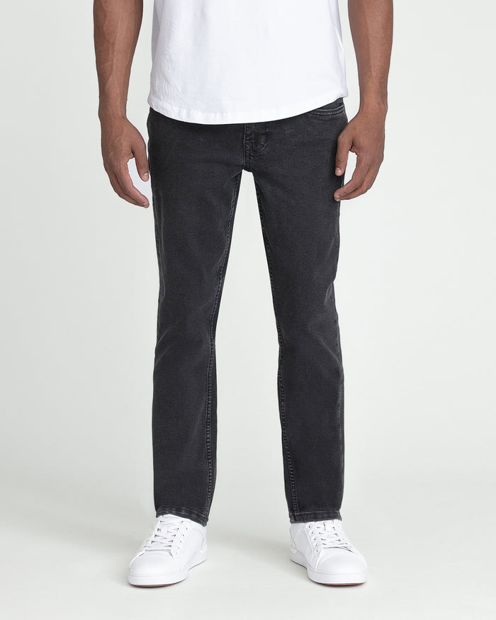 Man wearing white t-shirt and faded black slim fit jeans with white sneakers.