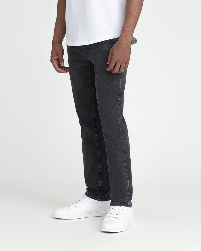 Man wearing white t-shirt and faded black slim fit jeans with white sneakers.