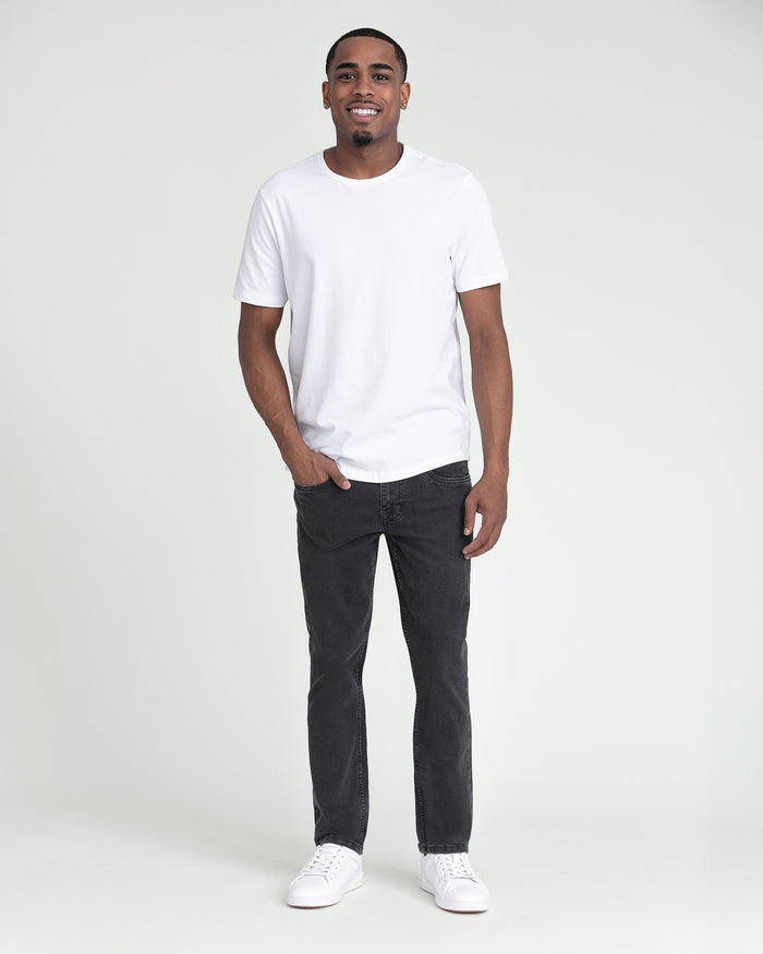 Man wearing white short-sleeve t-shirt with faded black slim fit jeans and white sneakers.