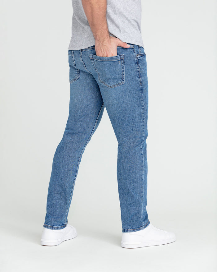 Medium blue slim fit jeans worn with a gray t-shirt and white sneakers.
