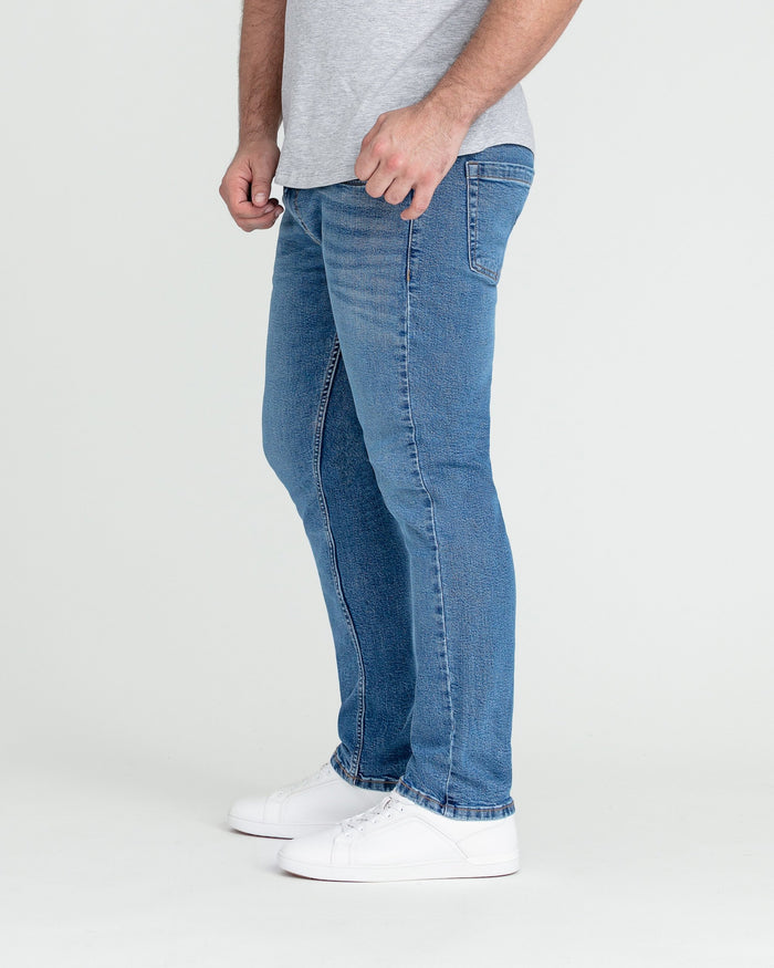Man wearing medium blue slim fit jeans with white sneakers and gray t-shirt.