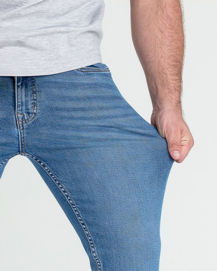 Man wearing light gray t-shirt and medium blue slim fit jeans, showing fit on torso and legs.