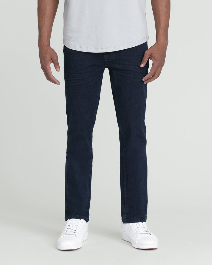 Man wearing white t-shirt and dark blue slim fit jeans with white sneakers.