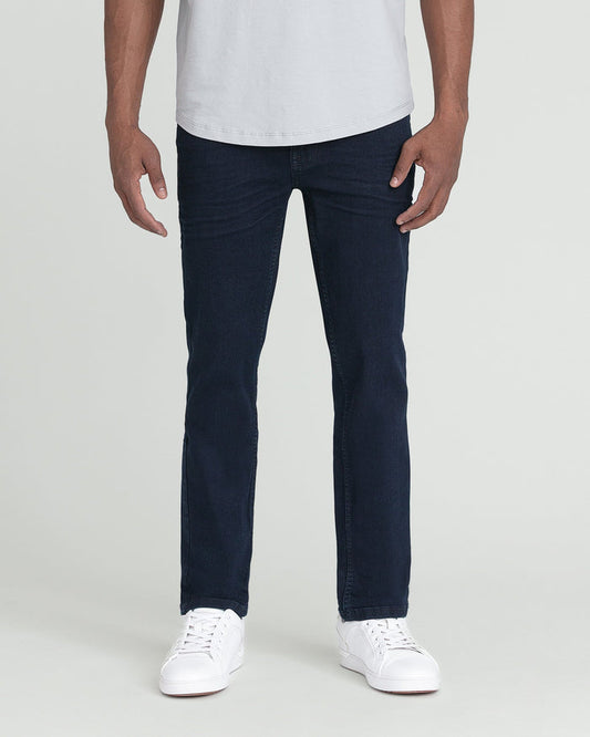 Man wearing white t-shirt and dark blue slim fit jeans with white sneakers.