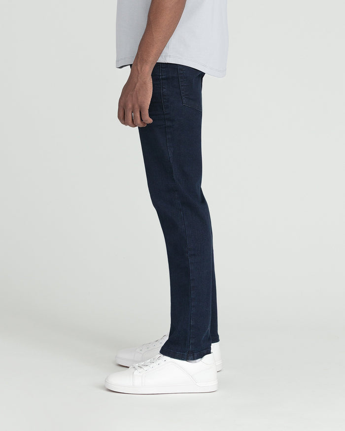 Man wearing deep blue slim fit jeans with white sneakers and light gray t-shirt.