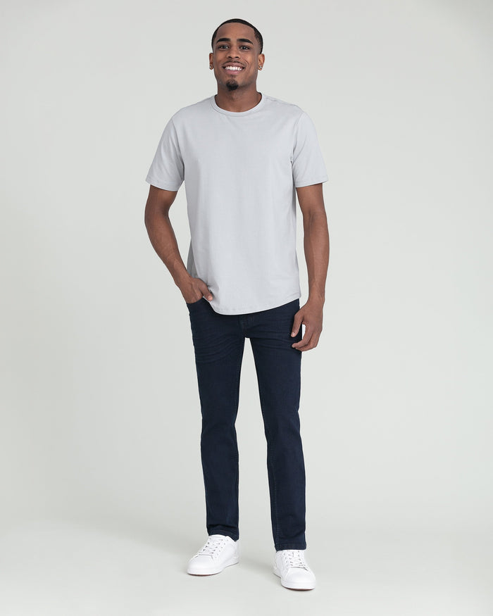 Man wearing white short-sleeve t-shirt and deep blue slim fit jeans with white sneakers.