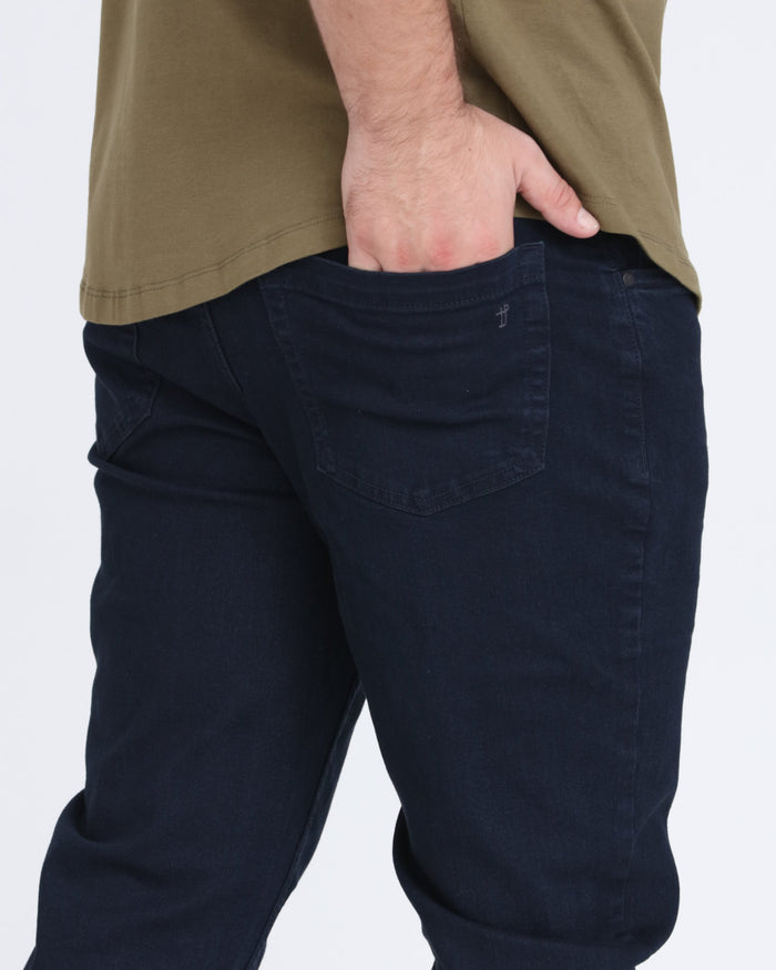 Deep blue slim fit denim jeans with back pocket detail, worn with tan shirt.