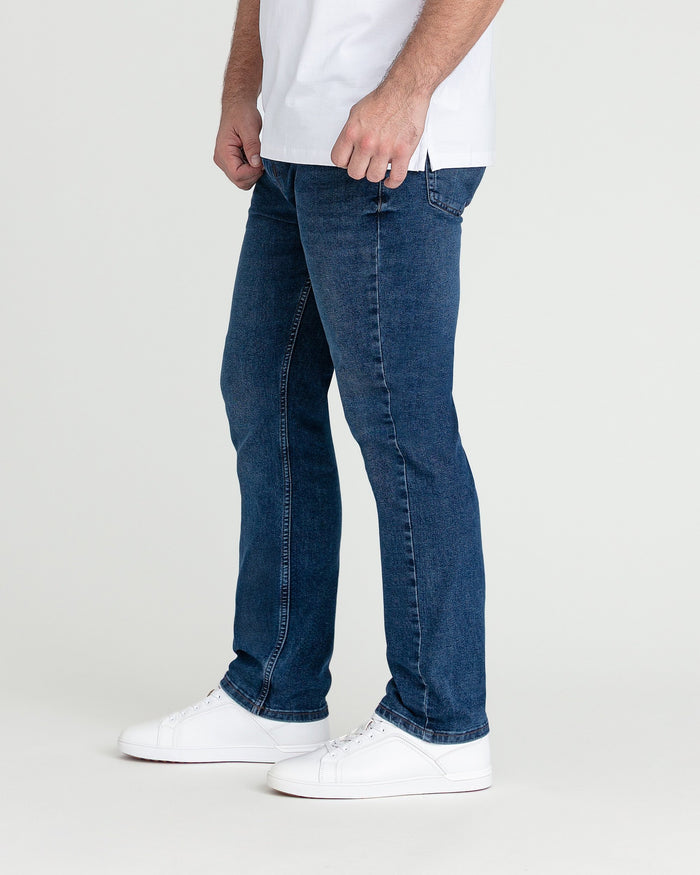 Men's medium blue slim fit jeans with white sneakers and white t-shirt.