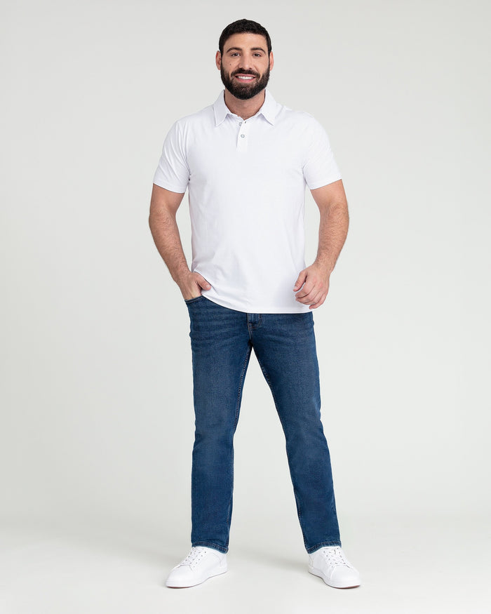 Man wearing white short-sleeve polo shirt and medium blue jeans with white sneakers.