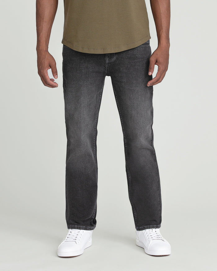 Man wearing olive t-shirt and charcoal slim-fit jeans with white sneakers.