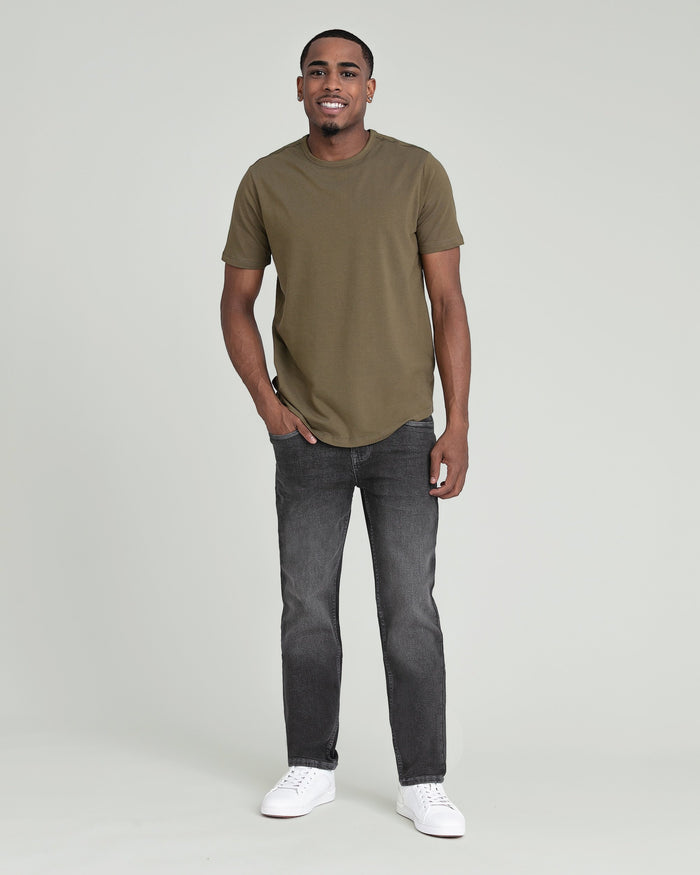 Man wearing olive green short-sleeve t-shirt with dark gray jeans and white sneakers.