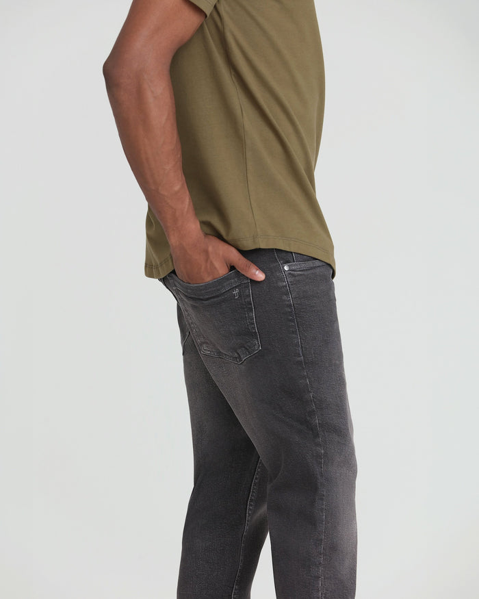 Man wearing khaki short-sleeve shirt and charcoal grey jeans, shown from the side.