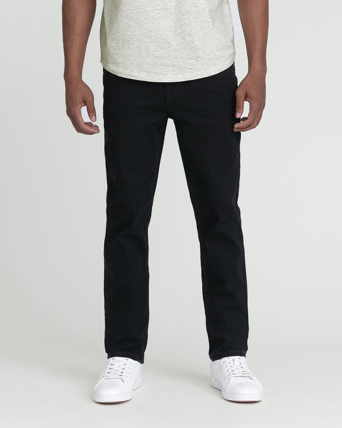 Man wearing light gray t-shirt and black slim fit jeans with white sneakers.