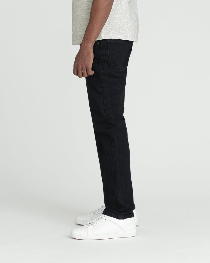 Black slim fit jeans with straight leg, worn with gray t-shirt and white sneakers.