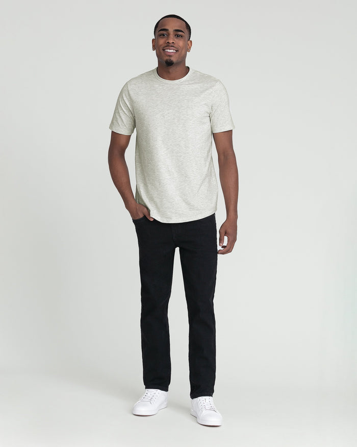 Man wearing light gray short-sleeve t-shirt and black slim-fit jeans with white sneakers.