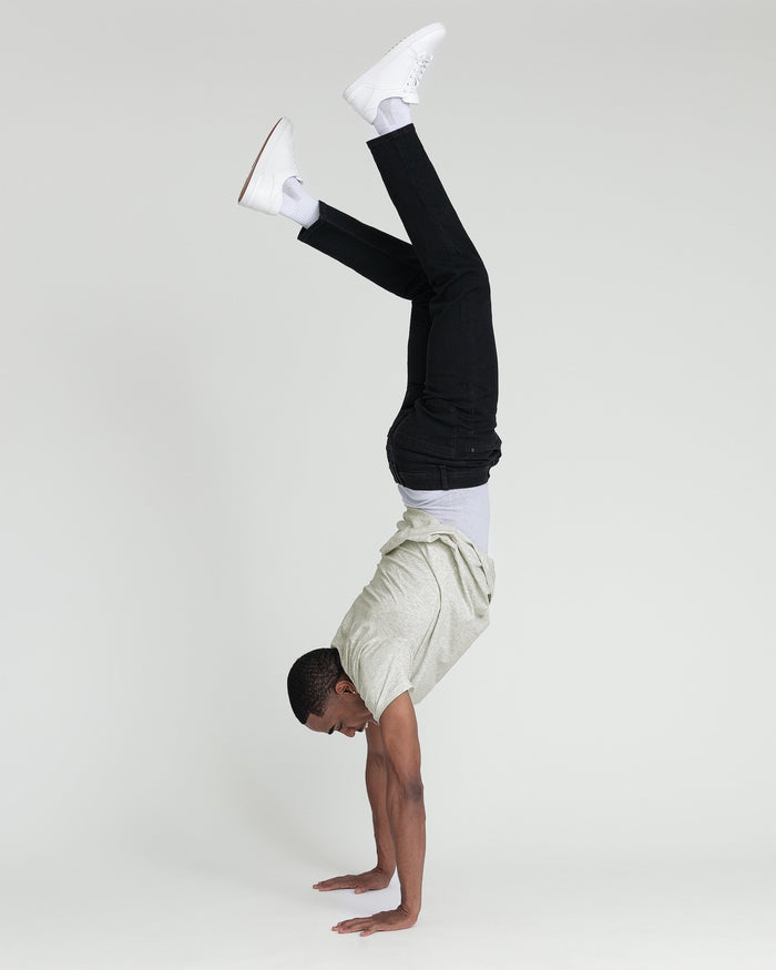 Person wearing black slim fit jeans with white sneakers and cream shorts, posed upside down.