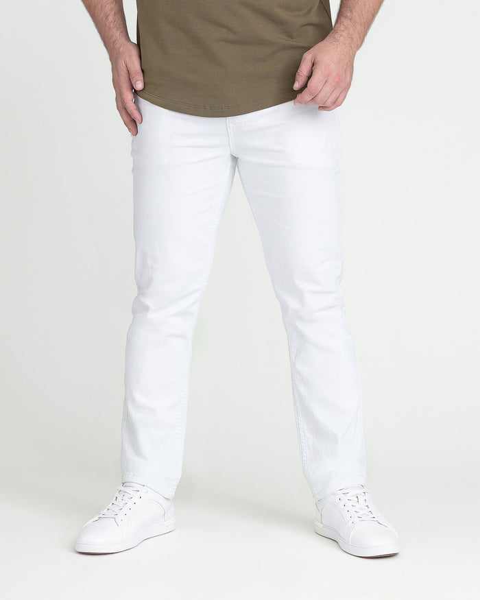 Man wearing white slim-fit jeans with olive green shirt and white sneakers.